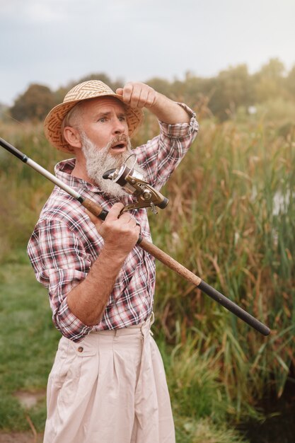 Homem barbudo sênior pescando em um lago