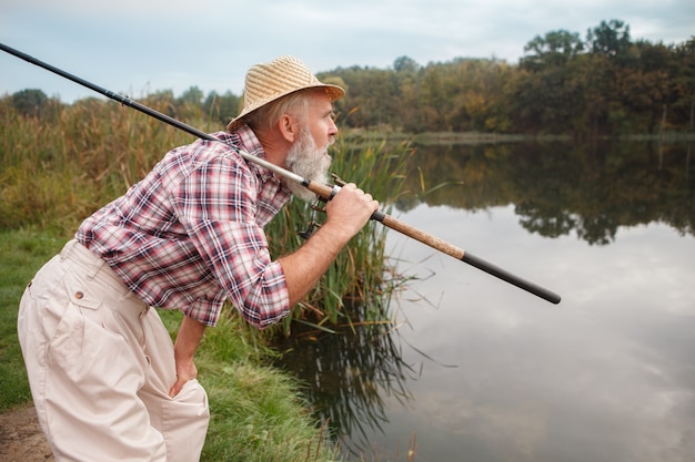 Homem barbudo sênior pescando em um lago