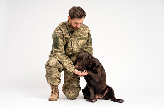 Homem barbudo soldado treinando cão Labrador isolado em fundo branco