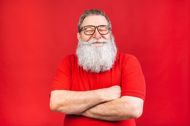 Homem barbudo sorridente com óculos em uma camiseta vermelha isolado em um fundo vermelho