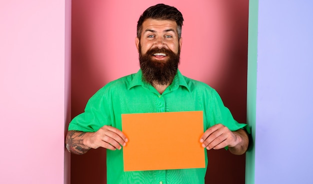 Homem barbudo sorridente com pequena placa de publicidade. banner de publicidade com espaço de cópia para texto.