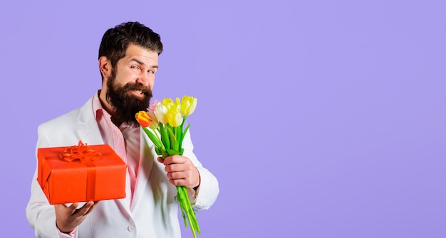 Homem barbudo sorridente com presente e buquê de tulipas caixa de presente buquê de flores flores da primavera