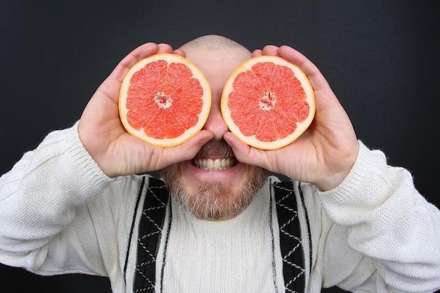 Homem barbudo sorridente com uma toranja cortada nas mãos