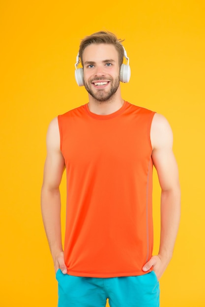 Homem barbudo sorridente ouve música em fones de ouvido digitais vestindo roupas esportivas para treinamento de treino