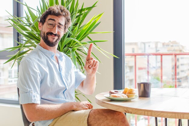 Homem barbudo sorrindo com orgulho e confiança fazendo a pose número um triunfantemente, sentindo-se um líder