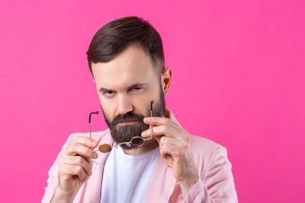 Homem barbudo vestido com uma jaqueta rosa com óculos Retrato de estúdio emocional