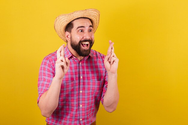 Homem barbudo vestindo roupas típicas para festa Junina Foto aproximada Dedos cruzados desejando torcendo para desejar tanta sorte Para a Festa do Arraia