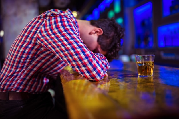 Homem bêbado deitado no balcão de bar