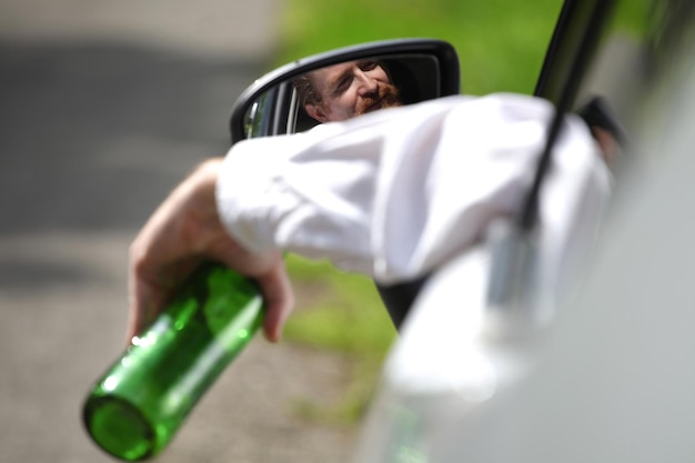 Foto homem bêbado no carro com uma garrafa de álcool