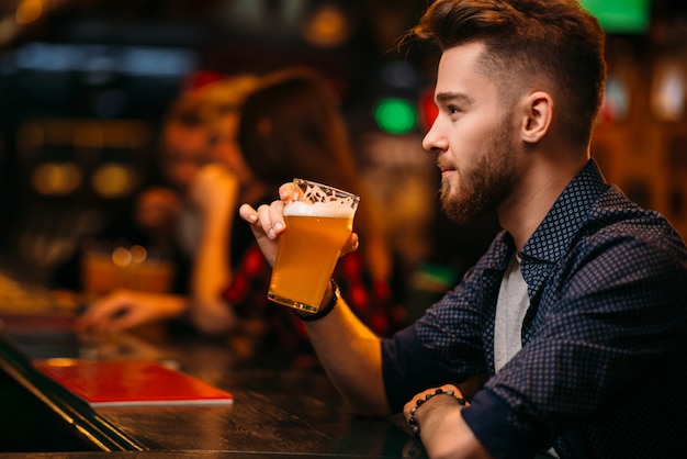 Homem bebe cerveja no balcão de um bar esportivo