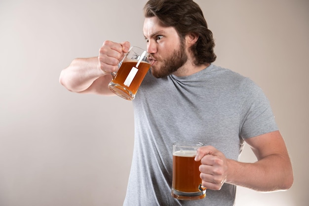 Foto homem bebendo cerveja isolado em fundo cinza claro
