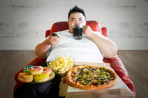 Foto homem bebendo enquanto está sentado com vários alimentos na mesa em casa