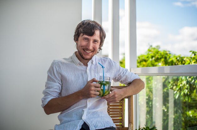 Homem bebendo um mojito no terraço.