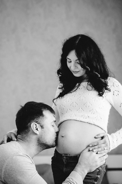 Homem beijando e abraçando a barriga em casa