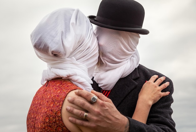 Homem beijando mulher com tecidos brancos na cabeça