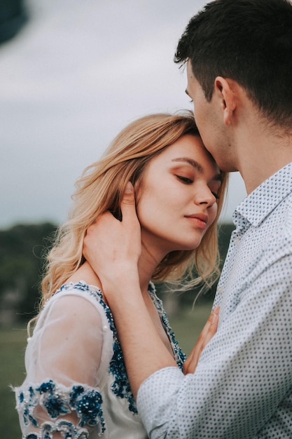 Homem beijando mulher enquanto está de pé contra o céu