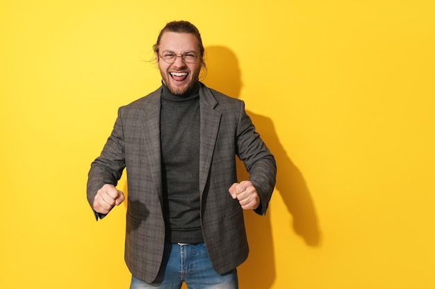 Homem bem sucedido alegre usando óculos contra fundo amarelo