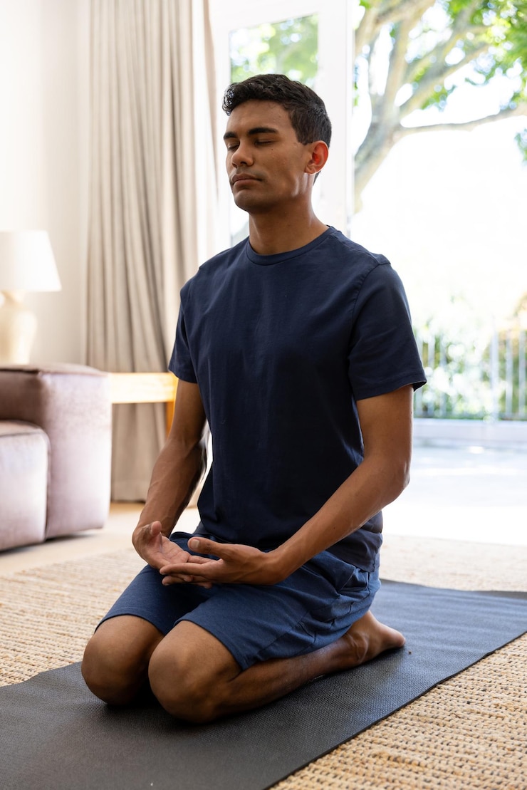 Foto homem biracial fazendo ioga e meditando em casa