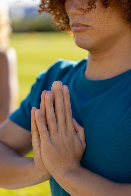 Homem birracial sentado na grama, fazendo ioga e meditando no jardim