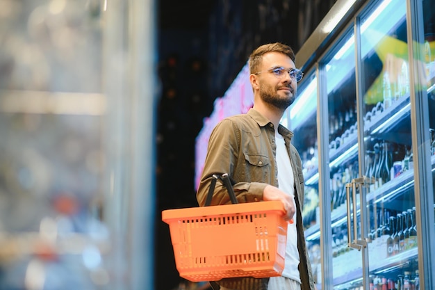 Foto homem bonito a fazer compras num supermercado.