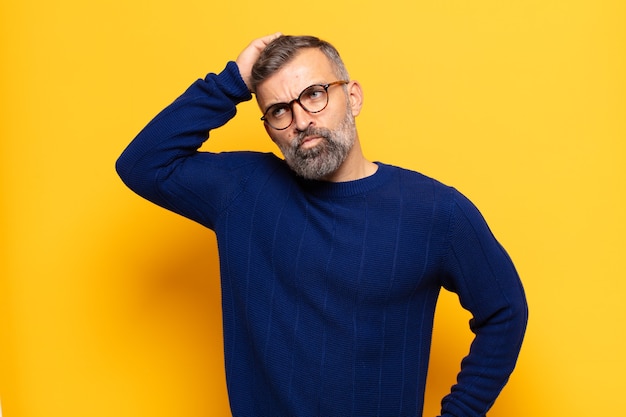 Homem bonito adulto perplexo e confuso, coçando a cabeça e olhando para o lado