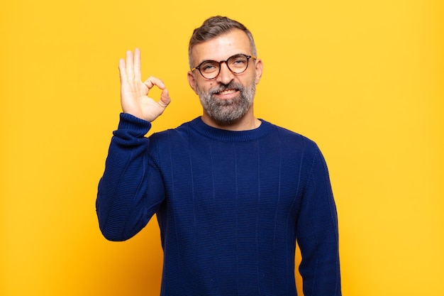 Homem bonito adulto se sentindo feliz, relaxado e satisfeito, mostrando aprovação com gesto bem, sorrindo