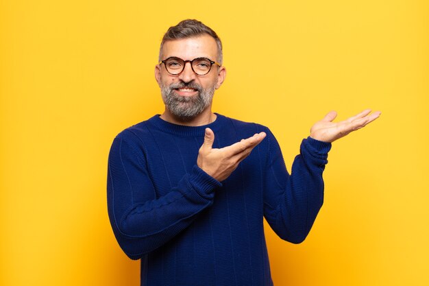 Homem bonito adulto sorrindo com orgulho e confiança, sentindo-se feliz e satisfeito e mostrando um conceito no espaço da cópia