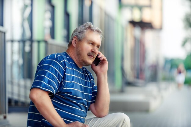 Homem bonito adulto usa um smartphone o conceito de comunicação e tecnologia Homem falando ao telefone na cidade