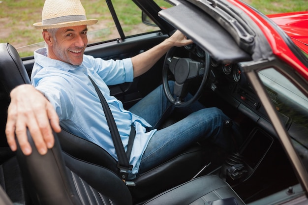 Homem bonito alegre posando em conversível vermelho