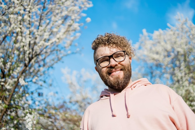 Foto homem bonito ao ar livre retrato em fundo flores de cerejeira ou flores de maçã e céu azul de primavera