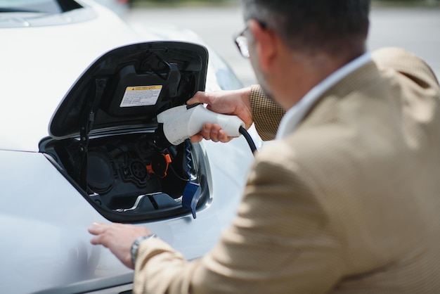 Homem bonito ao carregar o carro elétrico