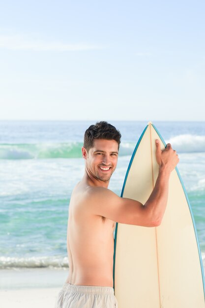 Homem bonito ao lado do mar com sua prancha de surf