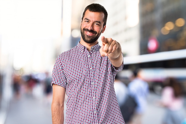 Homem bonito apontando para a frente em um fundo sem foco