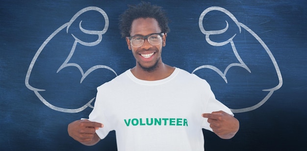 Foto homem bonito, apontando para sua camiseta voluntária contra a lousa azul