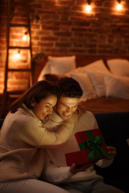 Homem bonito apresentando um presente para sua linda garota e sorrindo