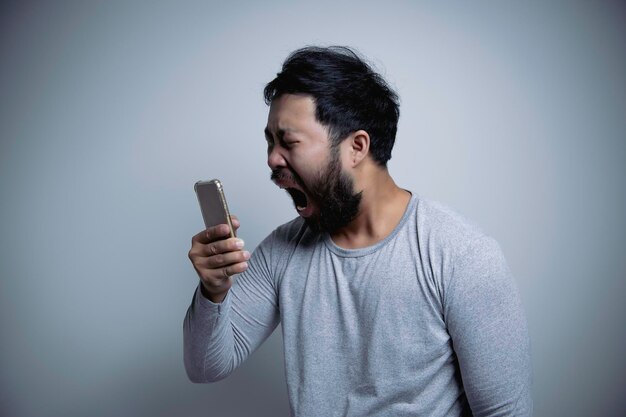 Homem bonito asiático com raiva em fundo brancoretrato de jovem conceito masculino de estresse mau humor depois de falar ao telefone