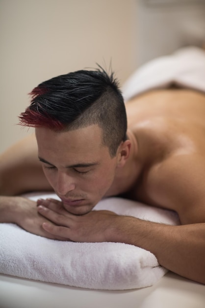 Foto homem bonito atraente descansando em um centro de massagem spa, deitado na mesa relaxando o conceito de olhos fechados de homens beleza cuidados de saúde