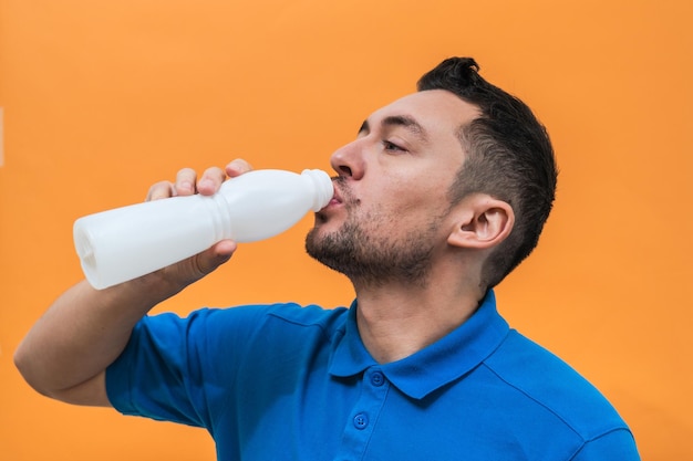 Homem bonito bebe iogurte ou leite em fundo laranja Mock up espaço de cópia