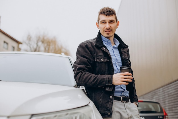 Homem bonito, bebendo café em seu carro