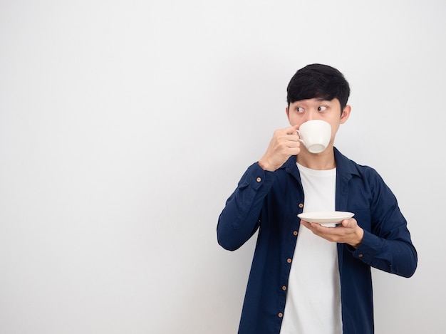 Homem bonito bebendo uma xícara de café e olhando para o lado do espaço de cópia no fundo branco