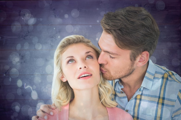 Homem bonito beijando namorada na bochecha contra design de ponto de luz abstrato azul