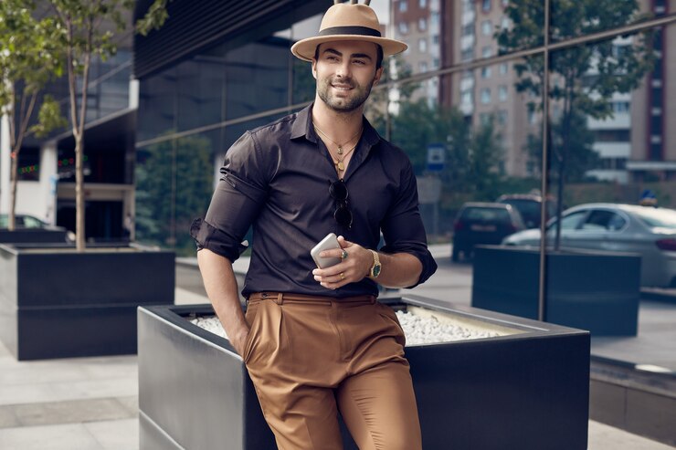 Foto homem bonito bronzeado hipster muscular brutal na camisa preta e chapéu com telefone