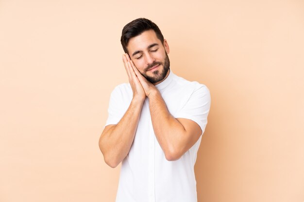 Homem bonito caucasiano em bege, fazendo o gesto do sono em expressão dorable