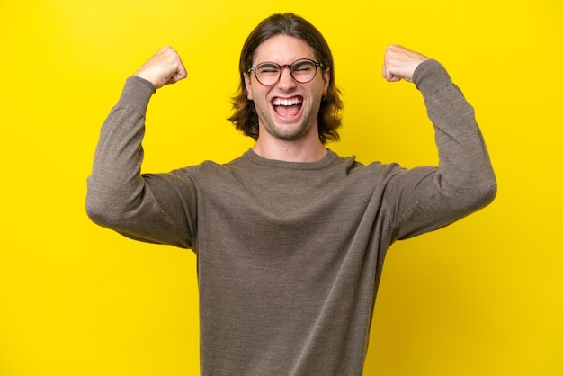 Homem bonito caucasiano isolado em fundo amarelo fazendo gesto forte