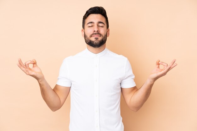 Homem bonito caucasiano na parede bege em pose de zen