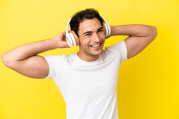 Homem bonito caucasiano sobre fundo amarelo isolado ouvindo música