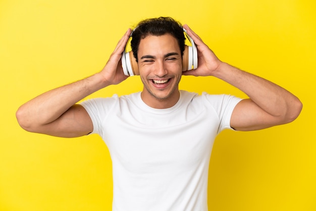 Homem bonito caucasiano sobre fundo amarelo isolado ouvindo música