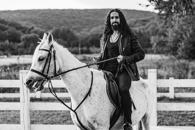 Homem bonito cavaleiro a cavalo Equestre monta seu cavalo branco bonito Homem bonito andando a cavalo na fazenda Macho atraente sentado no garanhão branco no rancho no outono