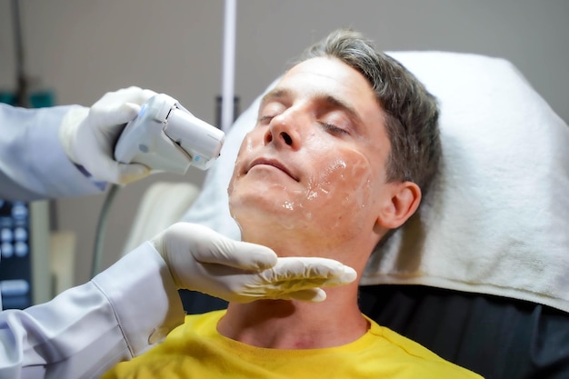 Homem bonito closeup tendo terapia de luz colorida para estimular a pele facial