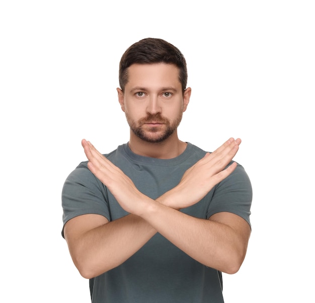 Homem bonito com as mãos cruzadas isolado em branco Gesto de parada